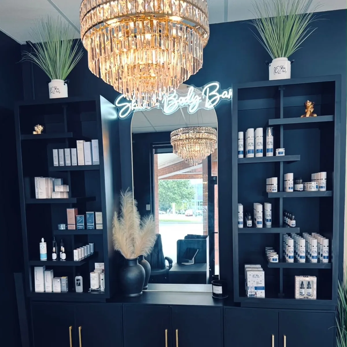 The Skin & Body Bar retail wall, navy shelves under a crystal chandelier